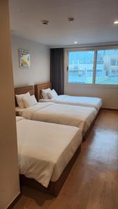 西归浦市Heyy Seogwipo Hotel的酒店客房设有三张床和窗户。
