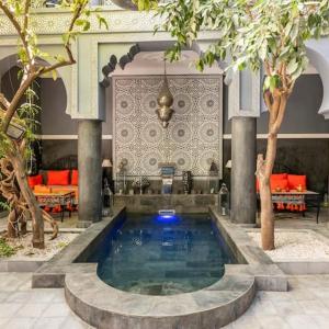 马拉喀什Riad des Mile Nuits的一座带树木和家具的建筑中的游泳池
