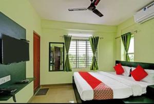 PānchuriaGoroomgo Green Oasis Inn Kolkata的一间卧室配有一张带红色枕头的床和一台电视。