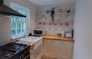 灵顿Stunning period cottage的厨房配有水槽和炉灶