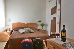 基安奇安诺泰尔梅马提尼酒店的一间卧室配有一张带两张行李箱的床和一瓶葡萄酒
