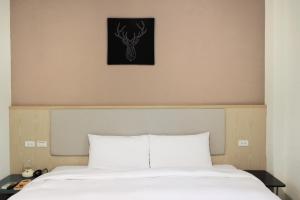 嘉义市偶然行旅的一张铺有白色床单的床和墙上的鹿的照片