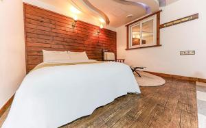 天安市Cheonan Business Hotel的卧室配有白色的床和木墙