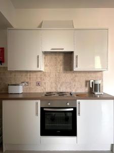 蒙特罗斯Central 2-bedroom apartment, Montrose的厨房配有白色橱柜和炉灶烤箱。