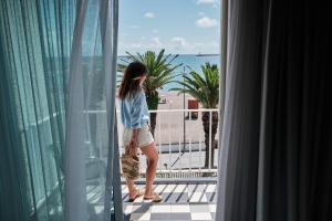 普拉亚达维多利亚Hotel Varandas do Atlântico by RIDAN Hotels的站在窗外的阳台上的女人