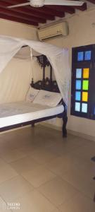 拉穆New Mahrus Hotel Lamu的窗户客房内的一张带天蓬的床