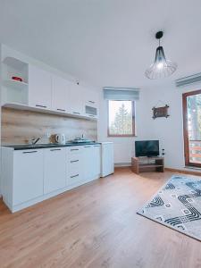 特拉夫尼克Apartments Planinski raj的厨房铺有木地板,配有白色橱柜。