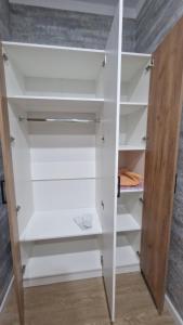 卡拉甘达Апартаменты в ЖК Мерей的配有白色架子和木门的衣柜