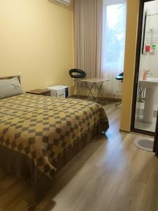 茨卡尔图博Guest House Kolkha的一间卧室配有一张床、一张桌子和一个窗户。