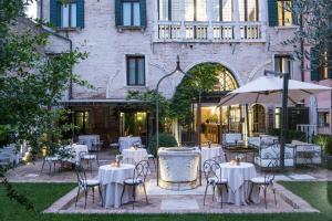 威尼斯纳尼莫切尼戈宫酒店的一间设有白色桌椅和遮阳伞的餐厅