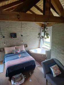 兰舒凯马杜O Chalé Encantado - Rancho Queimado的卧室配有1张床、浴缸和椅子