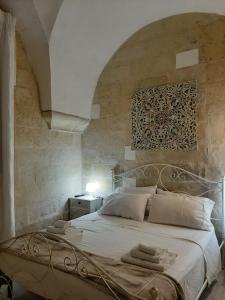 莱切Il Vico的卧室配有白色的床铺和石墙