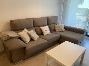 巴约讷Acogedor apartamento en Baiona的客厅配有一张棕色沙发,配有一张桌子