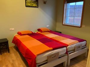 SkogarFagrafell Hostel的一间卧室配有一张带橙色和红色棉被的床