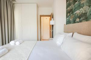 科罗尼佩鲁利亚海滩公寓式酒店的卧室配有白色床和毛巾