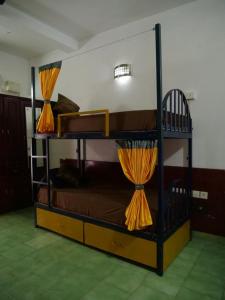 瓦尔卡拉Hosteller's的客房内的两张双层床位配有橙色窗帘