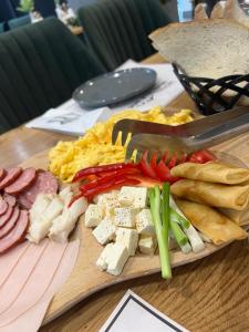 BorlovaHotel Muntele Mic的餐桌上的肉和蔬菜切板