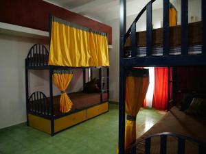 瓦尔卡拉Hosteller's的一间卧室设有两张双层床,配有黄色窗帘