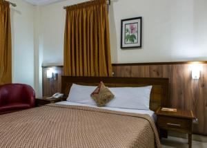 阿克拉Charleston Hotel的酒店客房,配有一张床和一张红色椅子