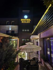 克拉约瓦Hotel Relax Craiova的晚上在酒店门前的一张桌子上摆放着一把遮阳伞