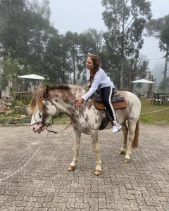 格拉玛多WoodStone Hotel Fazenda的骑着马的年轻女孩