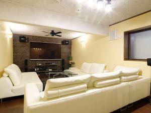 白马村白马五龙久留美酒店的客厅配有白色沙发和平面电视。