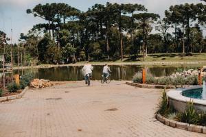 格拉玛多WoodStone Hotel Fazenda的两人在池塘旁的公园骑车