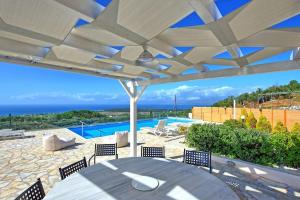 PíthosFamily Villa Portes with panoramic view!的一个带桌椅的庭院和一个游泳池