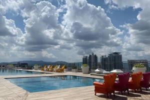 吉隆坡Skypool Couple Suite in Sri Hartamas KL的一座带椅子的建筑屋顶上的游泳池