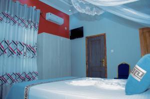 布琼布拉Kinindo Light Hotel的一间卧室设有一张床和红色及白色的墙壁
