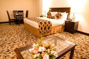 伊斯兰堡Hotel Hillview Islamabad的配有床和鲜花桌的酒店客房