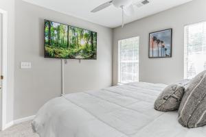 查尔斯顿Lowcountry haven - game rm + king bds, mins 2 dwtn的白色卧室设有一张床和墙上的电视