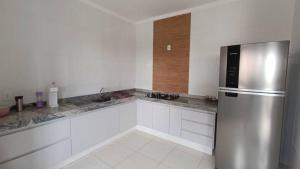 里约热内卢CASA 2 QUARTOS的厨房配有白色橱柜和不锈钢冰箱