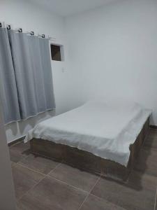 卡波布里奥Casa em Unamar, Cabo Frio - com piscina privativa的配有白色床单和窗帘的客房内的一张床位