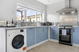 拉夫堡Lovely 2 Bedroom House with Parking的厨房配有蓝色橱柜、洗衣机和烘干机
