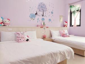 Fengping一宿來民宿的卧室内的两张床,墙壁上装饰着粉红色的墙壁和鲜花