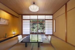 丰冈市常磐别馆的一间带桌椅和大窗户的用餐室