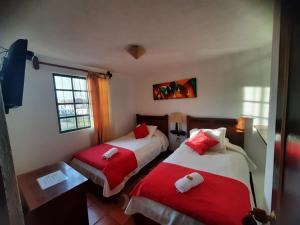 莱瓦镇Aparta Hotel El Refugio de María的一间卧室配有两张红色和白色床单