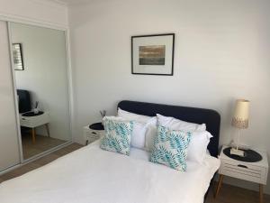 ManyanaConjola Inn-let - Self Contained Unit - Lake Conjola的卧室配有白色床和蓝色及白色枕头