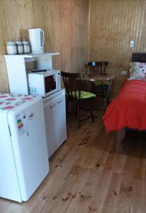 弗鲁蒂亚尔Cabaña Los Pajaritos dos de Frutillar的客房设有冰箱、桌子和床。