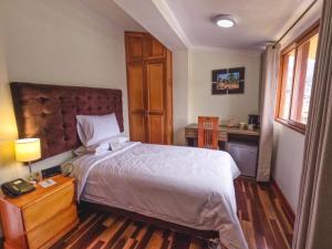 卡哈马卡Gran Kunturwasi Hotel Senior的一间卧室配有一张大床和一张书桌