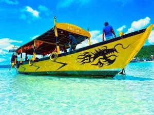 瓜隆岛Green Ocean Lodge的一条黄色的船,上面有一只龙,在水里画