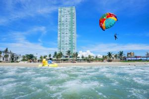 岘港Fusion Suites Da Nang - Daily Reflexology Inclusive的一个人在海滩上玩风筝