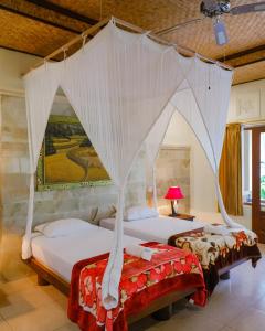 Menanga马哈吉利餐厅度假村的配有天蓬床的客房内的两张床