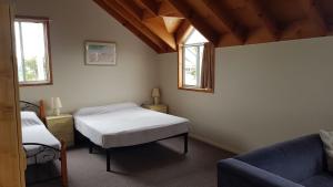 帽头镇Billungar Unit 1 at Hat Head的一间卧室配有一张床、一张沙发和两个窗户。