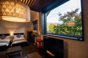 山形市ユニテ蔵王ジョーニダ リゾート的客房设有大窗户、一张床和电视。