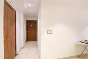 新德里FabHotel La Serene BnB的一条带白色墙壁和木门的走廊