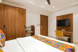 新德里FabHotel La Serene BnB的一间卧室配有一张床、一张书桌和一台电视
