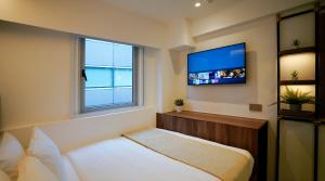 新加坡ST Signature Bugis Middle, SHORT OVERNIGHT, 11 hours 8PM-7AM的卧室配有一张床,墙上配有电视。