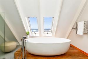 赫曼努斯港湾之家酒店的带窗户的浴室内的白色大浴缸